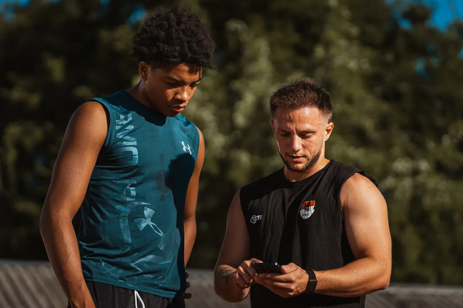 Kovács Martin egy sportolóval együtt nézi át az edzésadatokat a telefonon