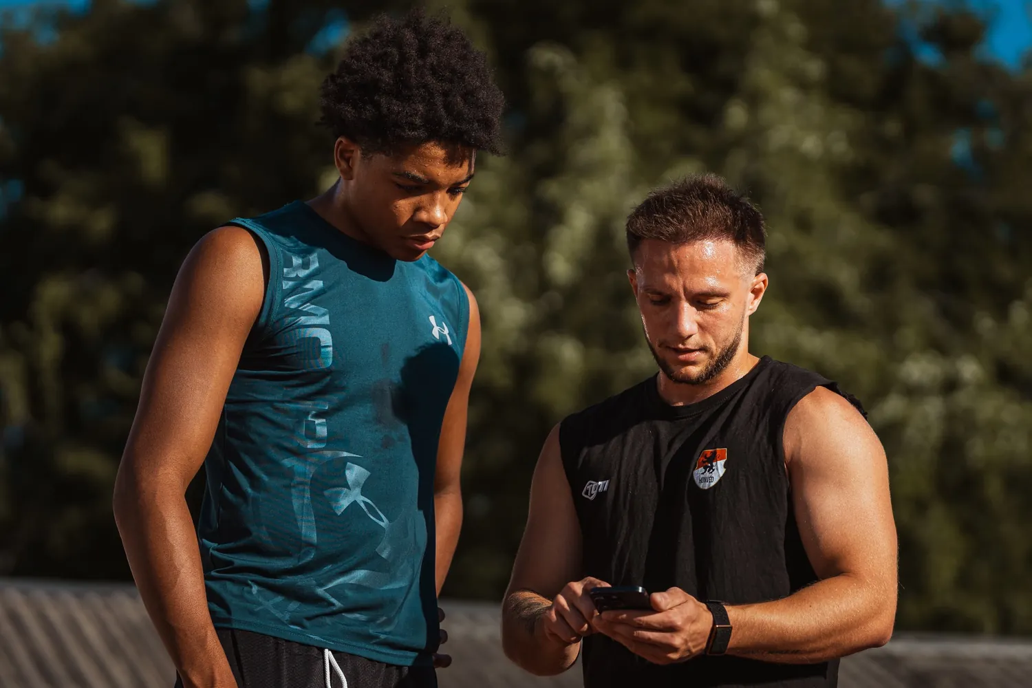 Kovács Martin egy fiatal sportolóval nézi az edzéstervet a telefonon