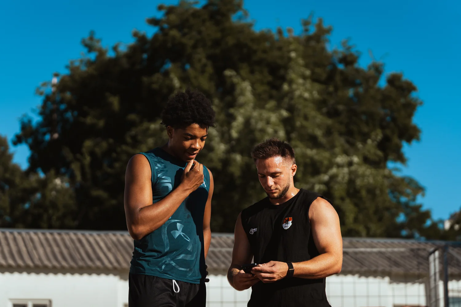 Kovács Martin egy sportolóval együtt nézi az edzésadatokat a telefonon